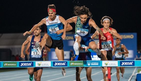 atletas federados saltando valla en pista atletismo